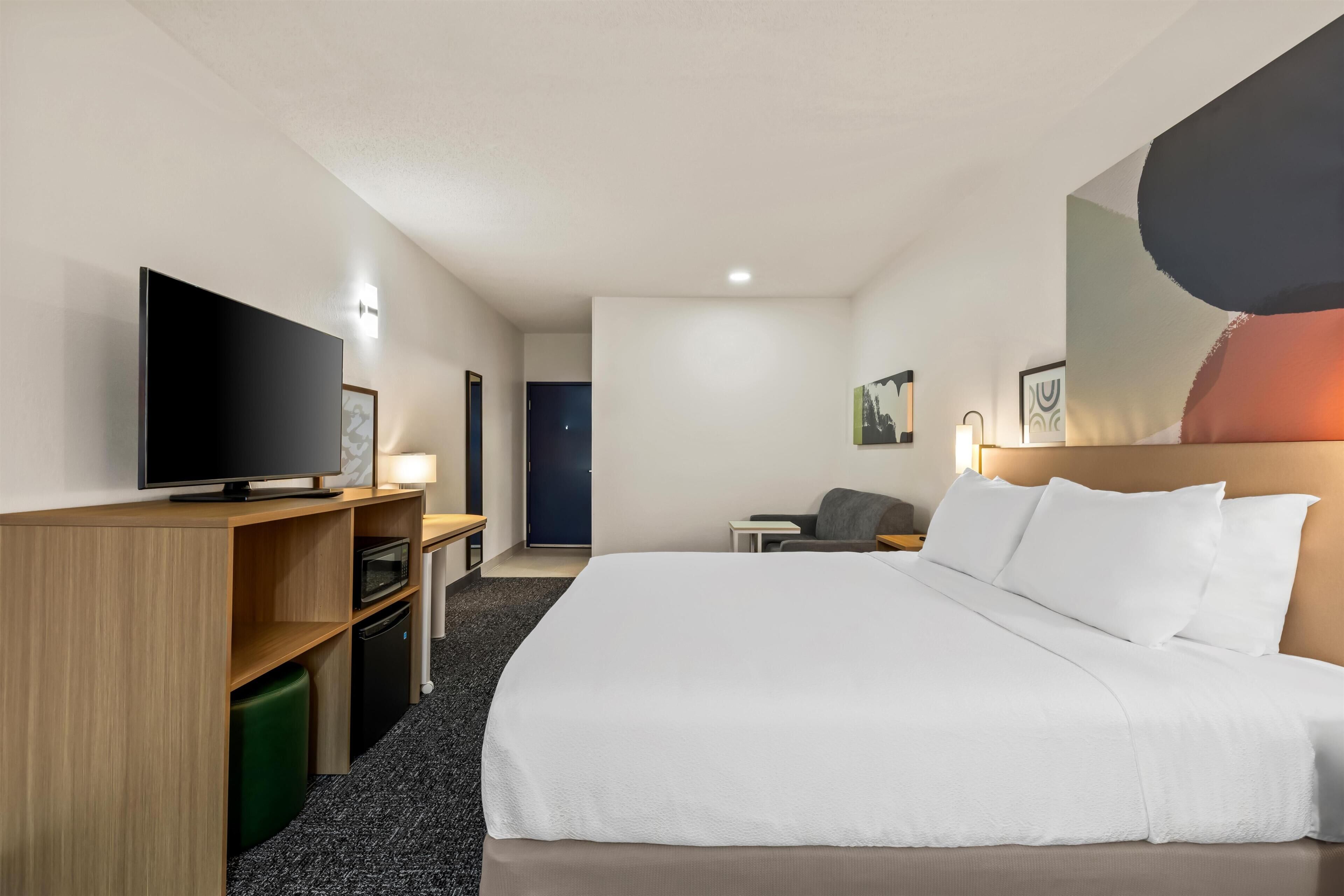 A hotel room with a bed, a television, a desk, and a chair.