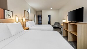 Habitación de hotel con dos camas, televisión, escritorio y una silla.