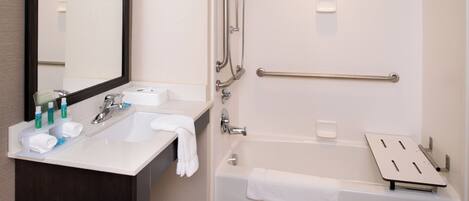 A modern bathroom with a sink, mirror, and bathtub.
