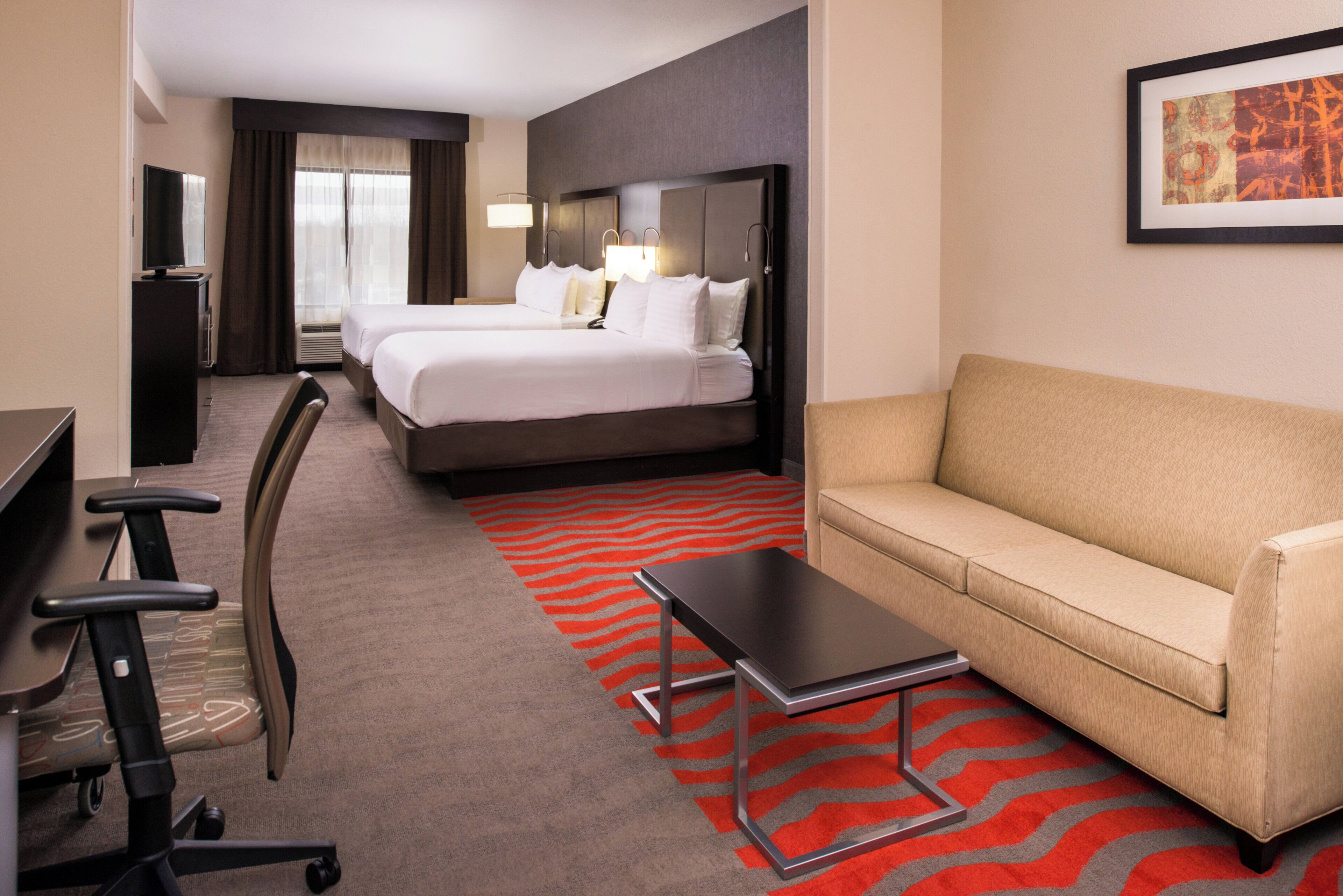 A hotel room with a bed, a sofa, a desk, and a chair.