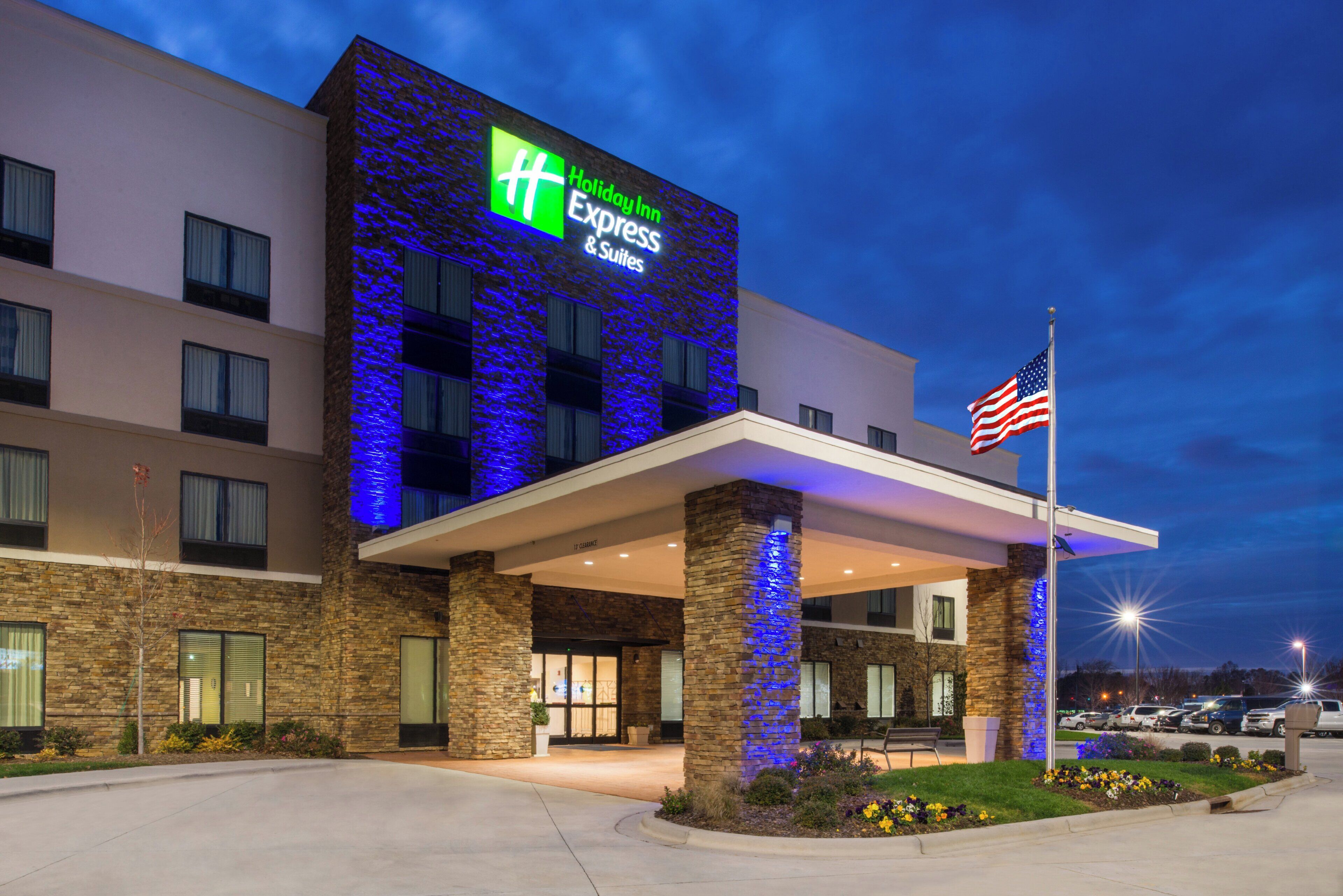 A Holiday Inn Express & Suites hotel with a stone facade and blue lighting.