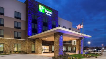 A Holiday Inn Express & Suites hotel with a stone facade and blue lighting.