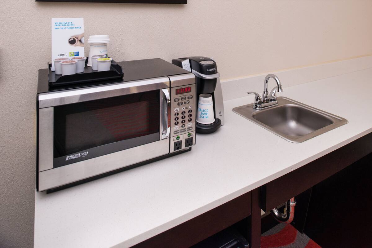 A kitchenette with a microwave, coffee maker, and sink.