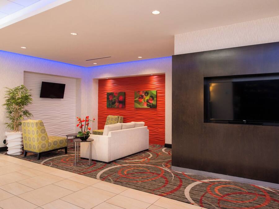 Eine moderne Lobby mit Flachbildfernseher, einer Couch, einem Sessel und einer Zimmerpflanze.