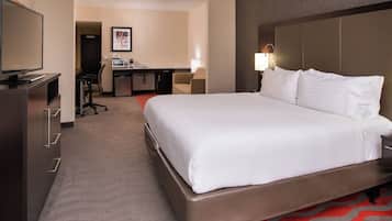 Une chambre d’hôtel avec un grand lit, un bureau avec une chaise, une télévision et une petite kitchenette.