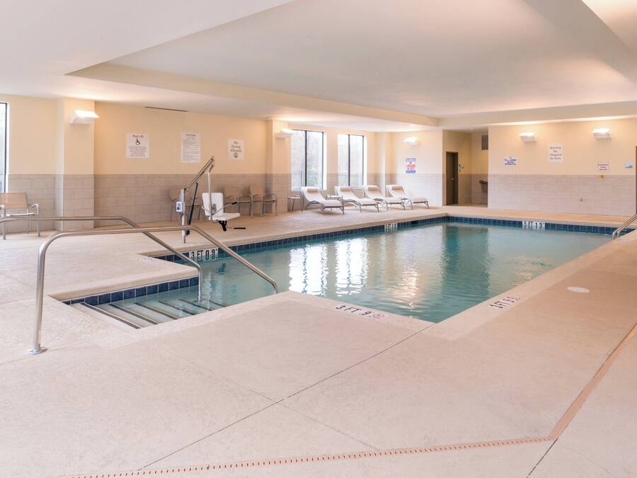 Una piscina interior con agua cristalina, indicaciones de profundidad marcadas y un elevador de piscina.