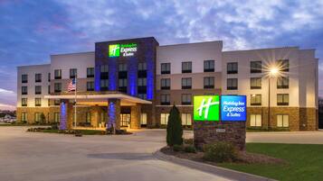 A Holiday Inn Express & Suites hotel with a stone facade, multiple windows, and an American flag.