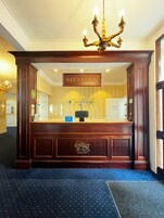 Un área de recepción con un mostrador de madera, un candelabro y un cartel que dice "RECEPTION".