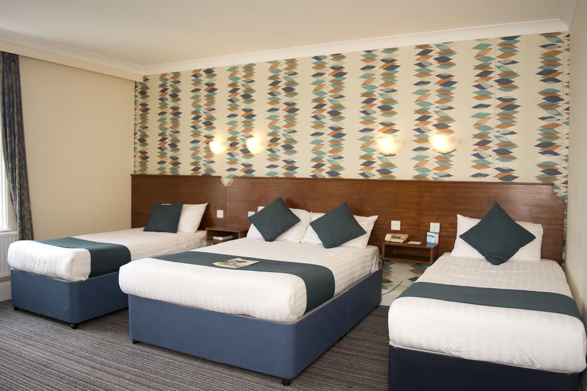 A hotel room with two beds, a wooden headboard, and a patterned wall.