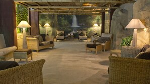 A spacious lobby with wicker furniture, a waterfall mural, and ambient lighting. - TLH Derwent Hotel - TLH Leisure, Entertainment and Spa Resort (Torquay)