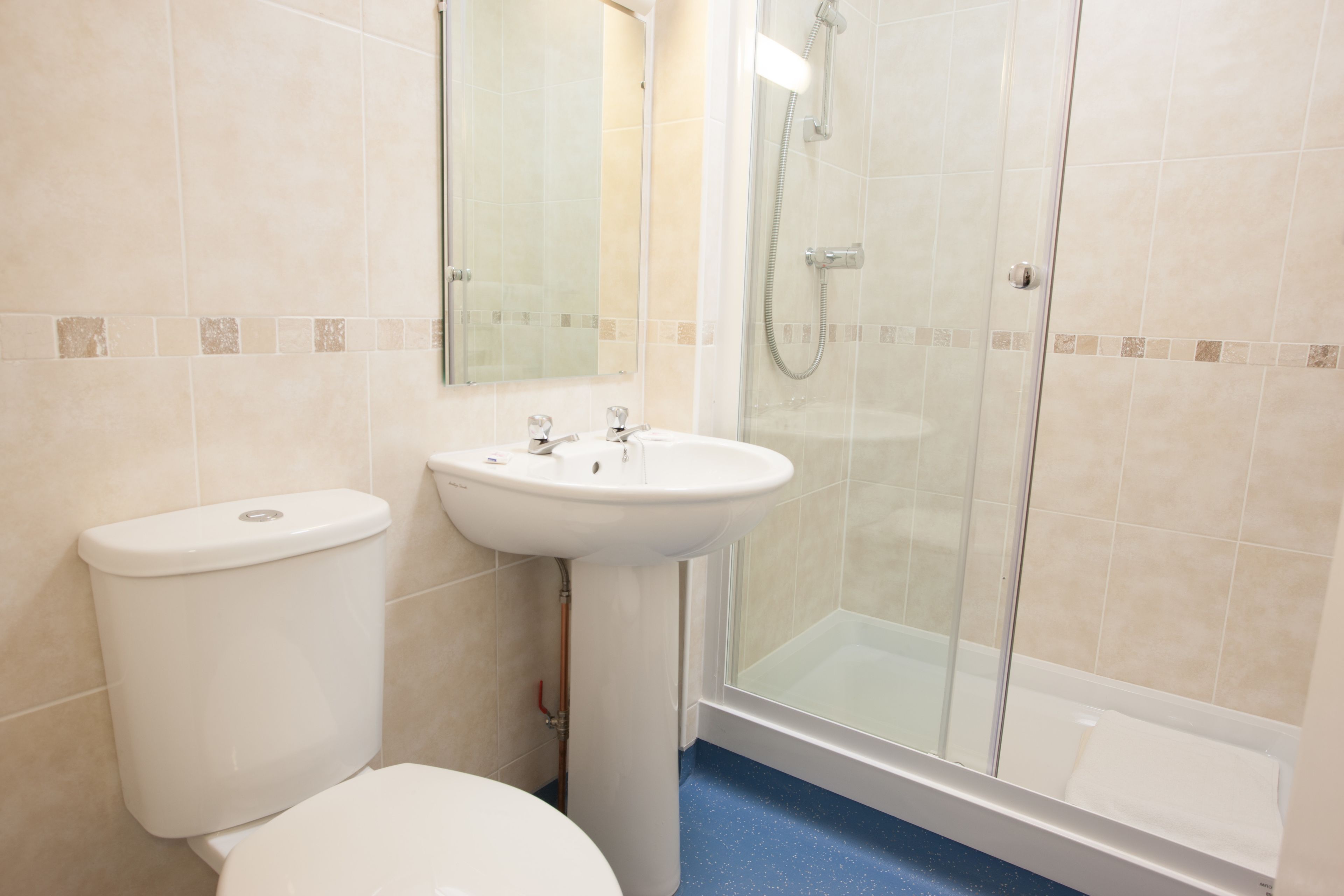 A bathroom with a toilet, sink, and glass-enclosed shower.