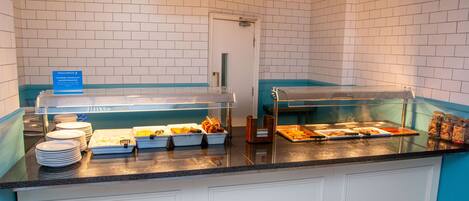 A buffet counter with labeled sections, a sign indicating 'Servery 1', and a variety of food items displayed.