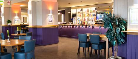 A restaurant with purple walls, wooden tables, and blue chairs.