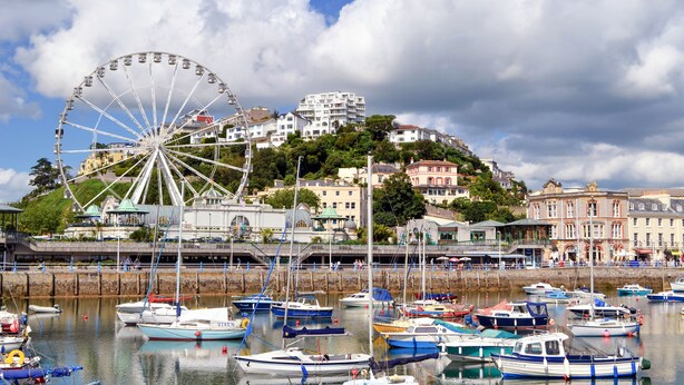 A harbor with boats docked, a large Ferris wheel, and buildings on a hill. - TLH Derwent Hotel - TLH Leisure, Entertainment and Spa Resort (Torquay)