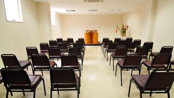 Une salle de conférence avec des rangées de chaises disposées face à un pupitre.
