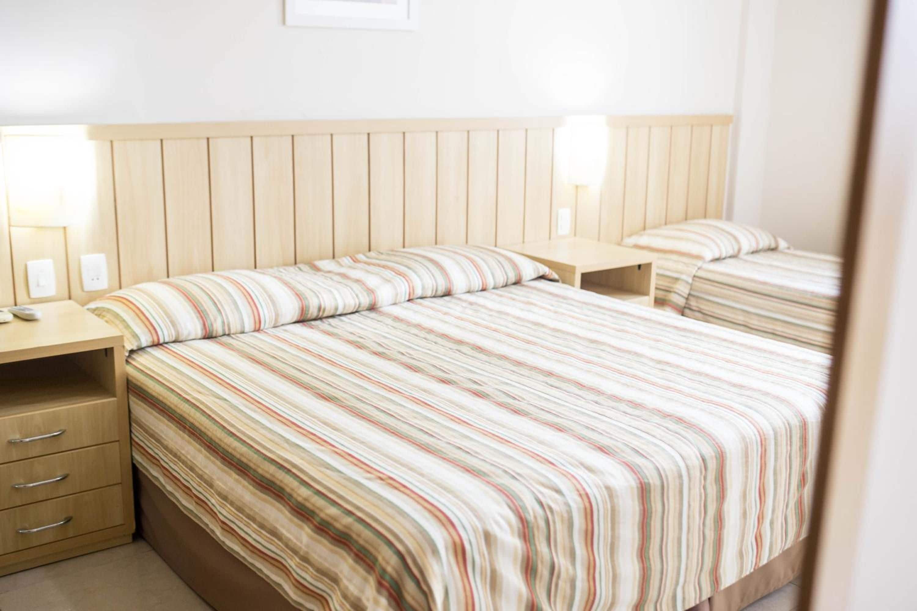 A hotel room with a large bed, two bedside tables, and a wooden headboard.