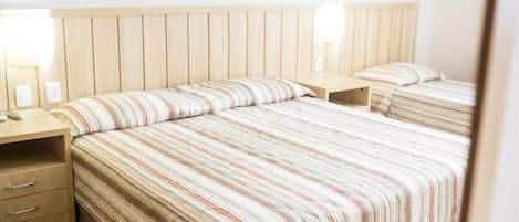 Una habitación de hotel con una cama grande, dos mesitas de noche y un cabecero de madera.