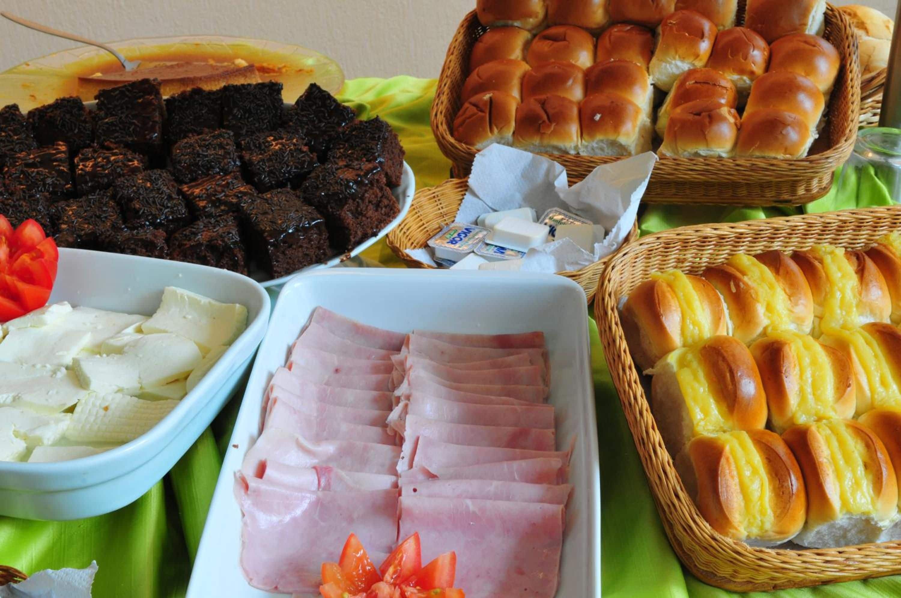 A buffet table with various food items including bread, ham, cheese, and a dish that appears to be a type of cake or dessert.