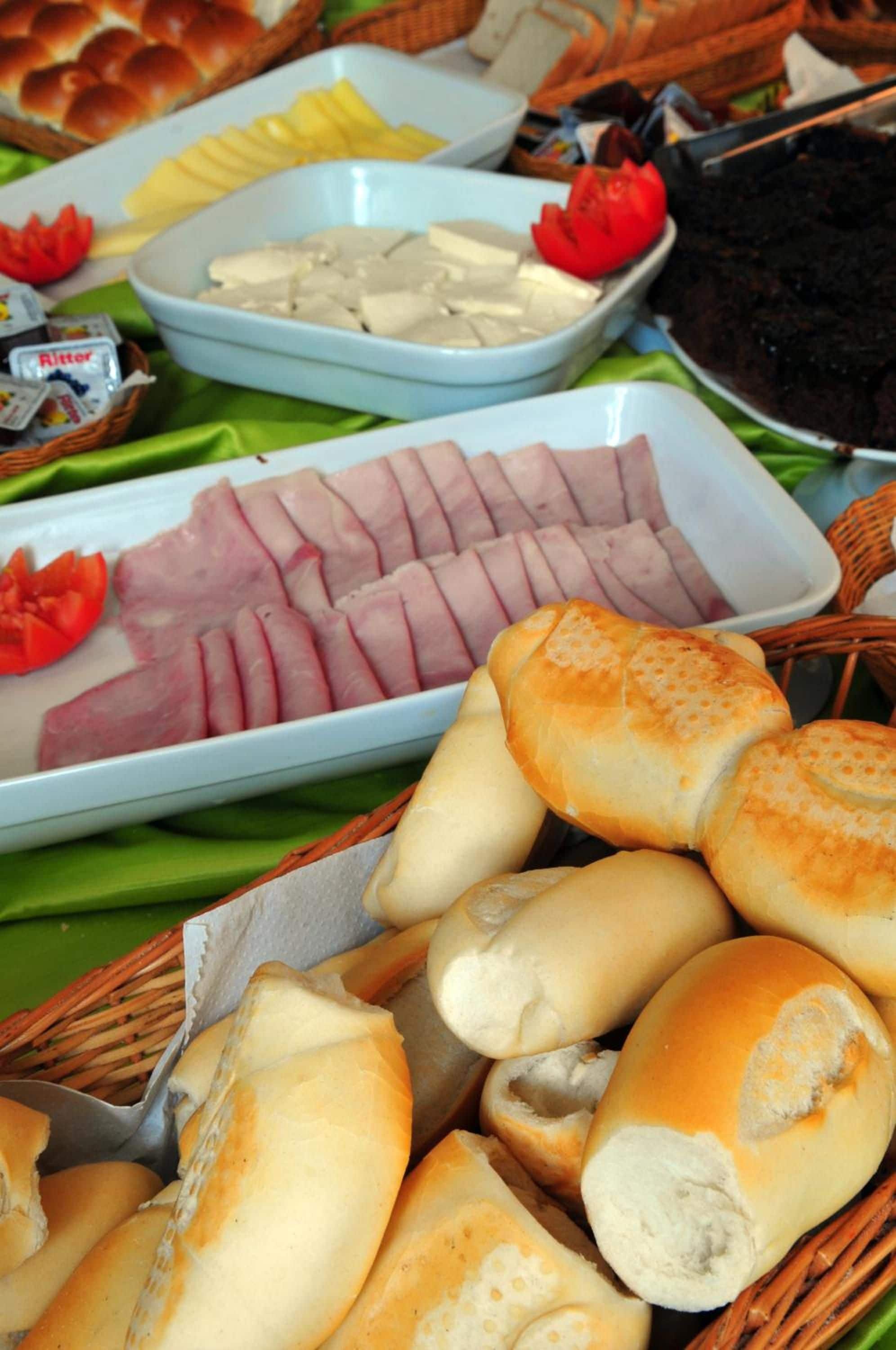 A buffet table with various food items including sliced meats, bread, and condiments.