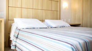 Une chambre d’hôtel avec un lit, une tête de lit en bois et un luminaire fixé au mur.
