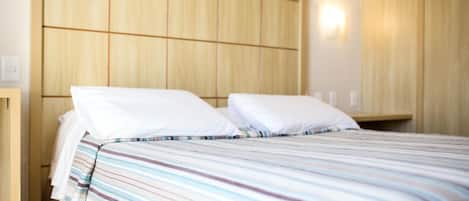 Una habitación de hotel con una cama, cabecera de madera y un aplique de pared.