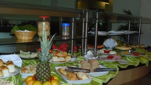 Un buffet proposant une variété de plats, notamment du pain, des fruits et des desserts.
