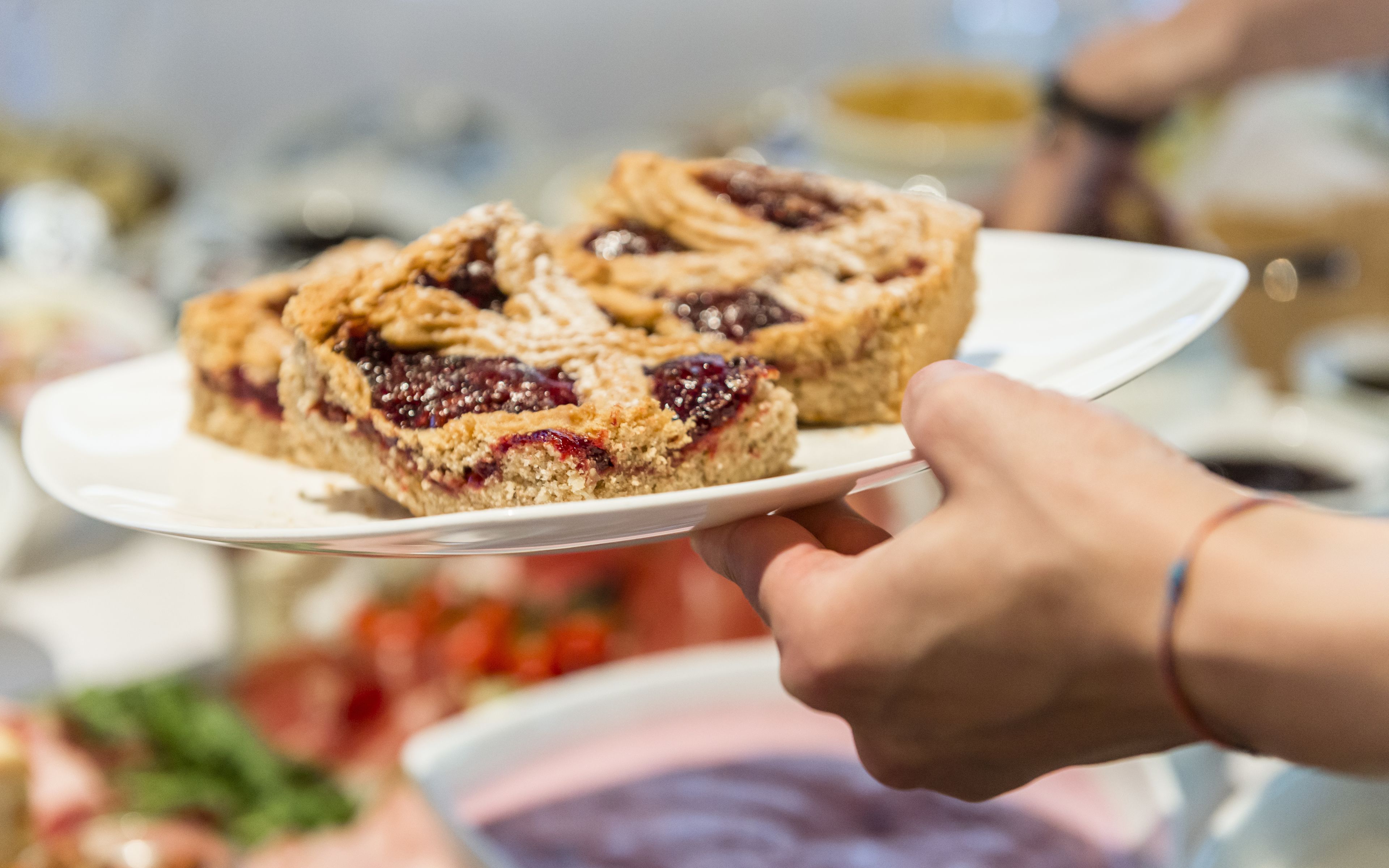 Eine Hand hält einen Teller mit einem Stück Kuchen.