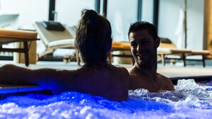 A couple in a hot tub with a view of lounge chairs and a window in the background. - Lener Wirtshaus & Hotel (Campo di Trens)