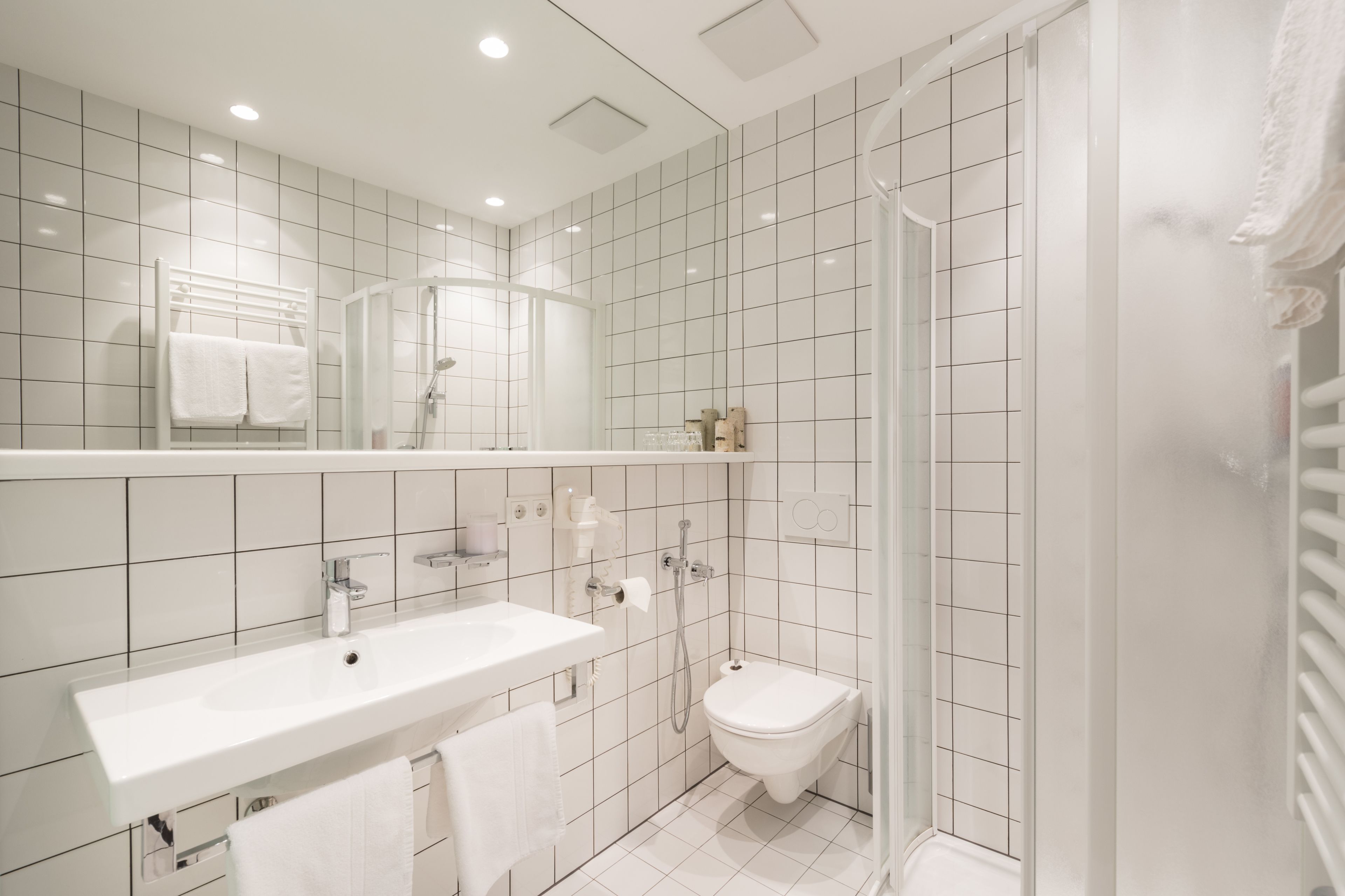 Een moderne badkamer met een wit wastafel, toilet en douche.