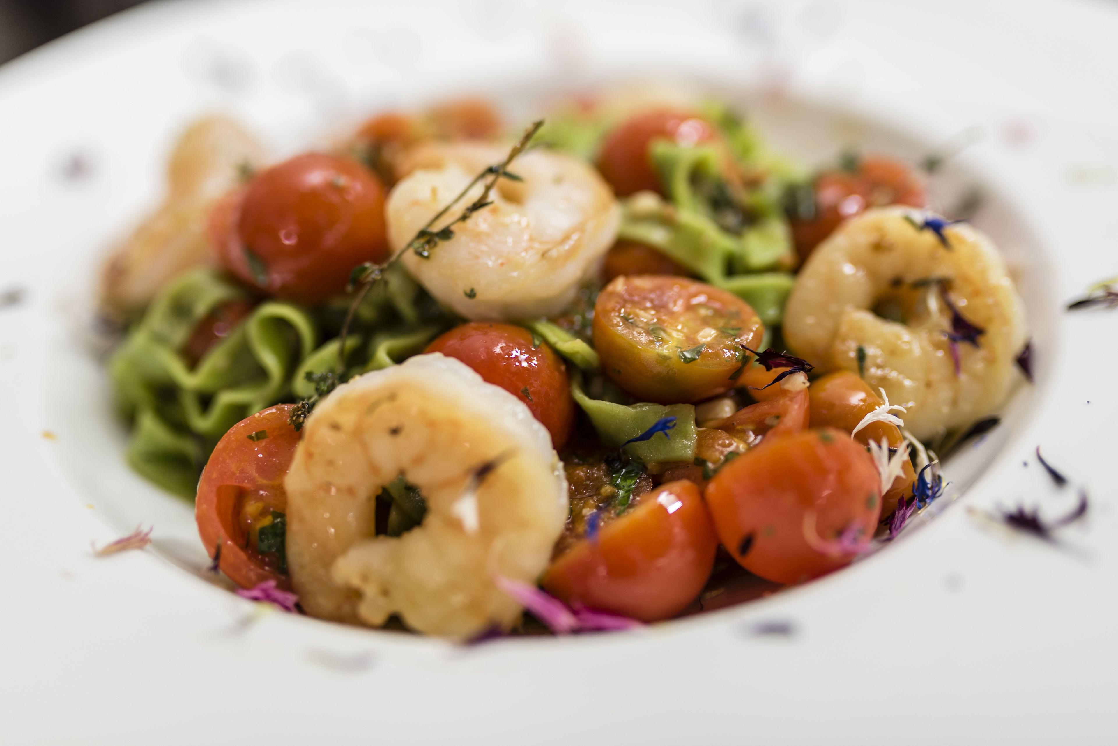 A plate of food with shrimp, cherry tomatoes, and greens.