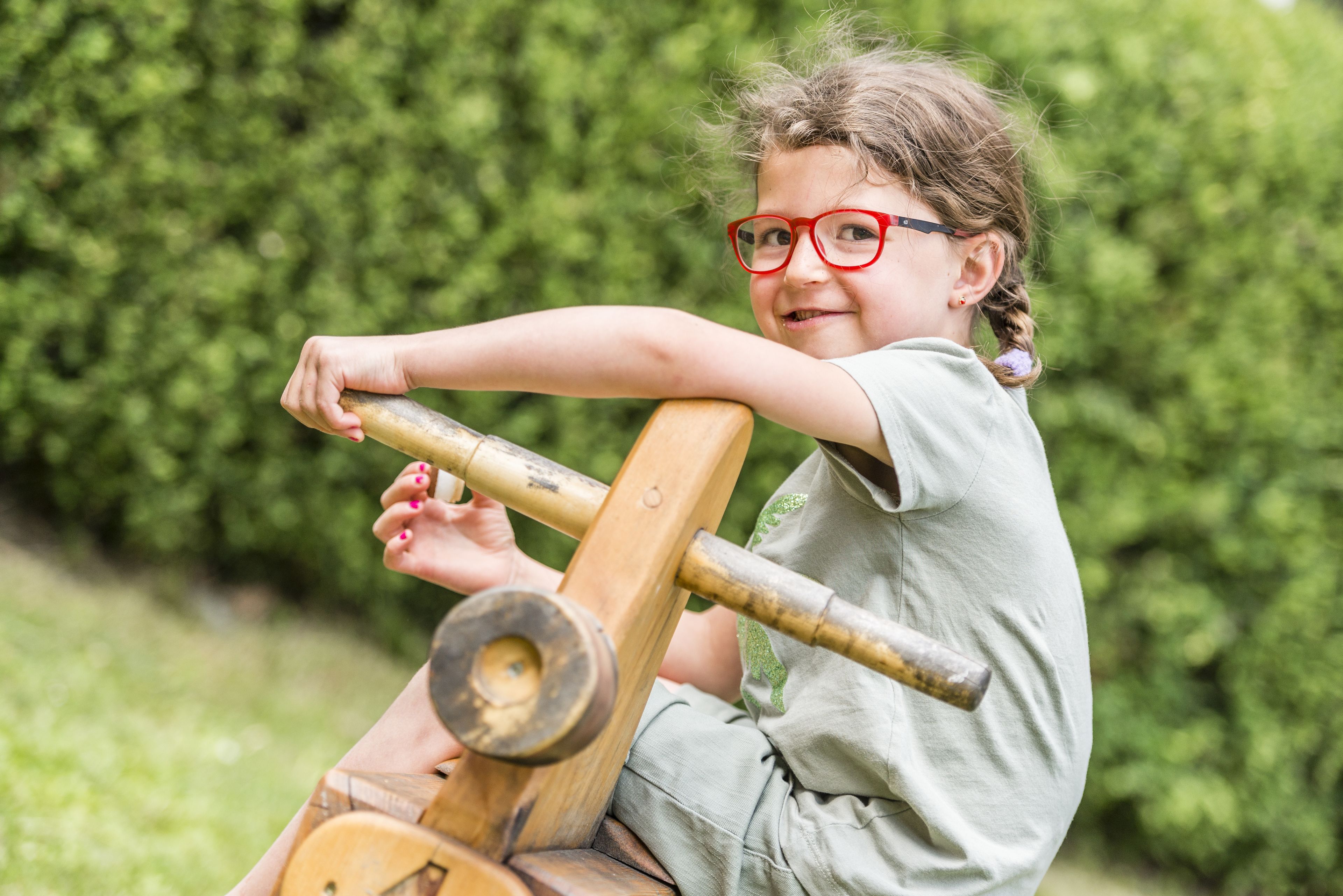 A child playing on a wooden seesaw in a garden.