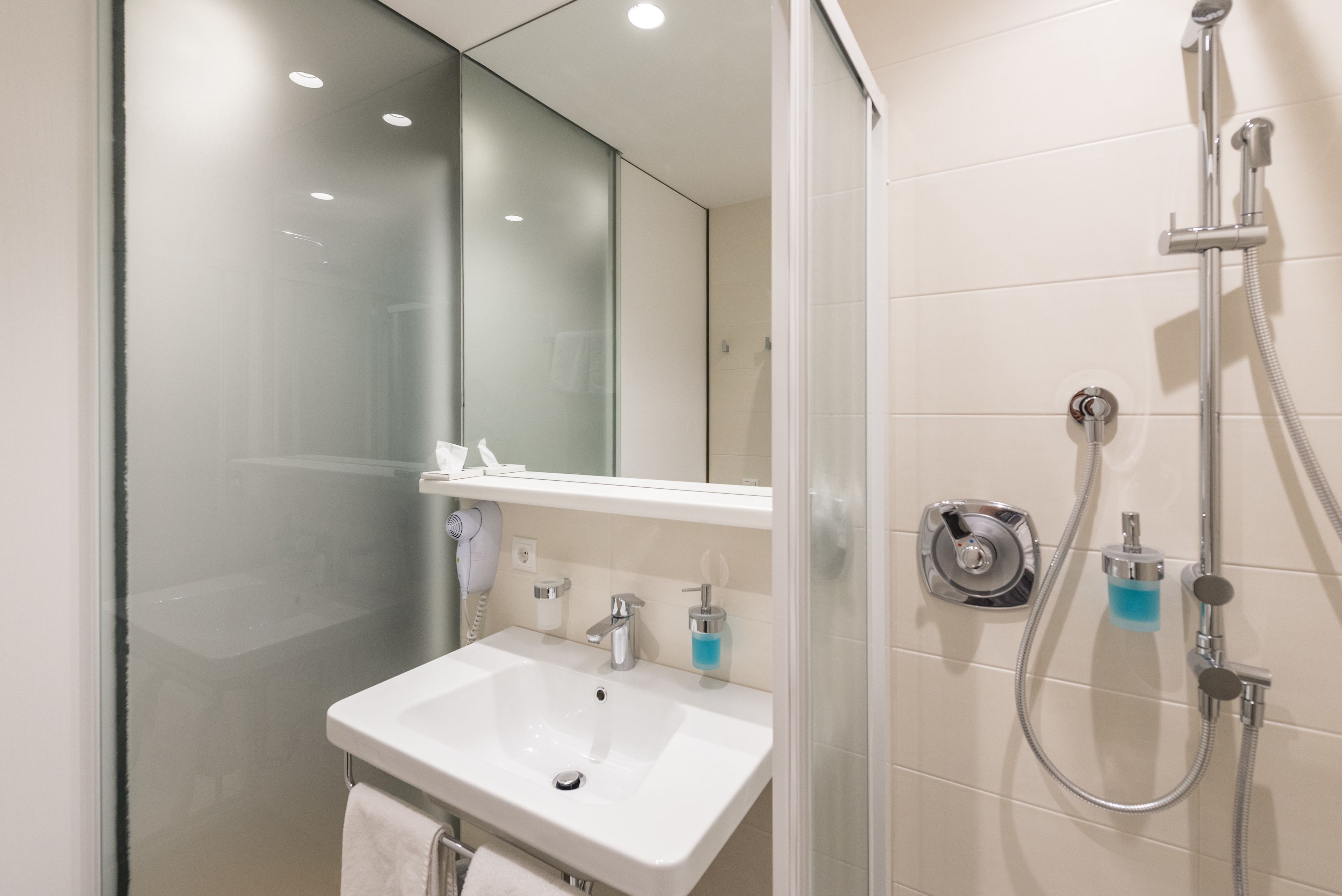 Een moderne badkamer met een douchecabine van glas, een wit wastafelmeubel en een spiegel erboven.