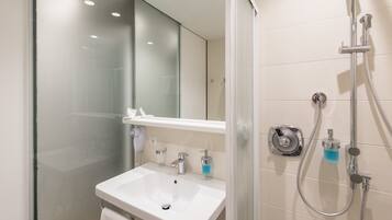 Een moderne badkamer met een douchecabine van glas, een wit wastafelmeubel en een spiegel erboven.