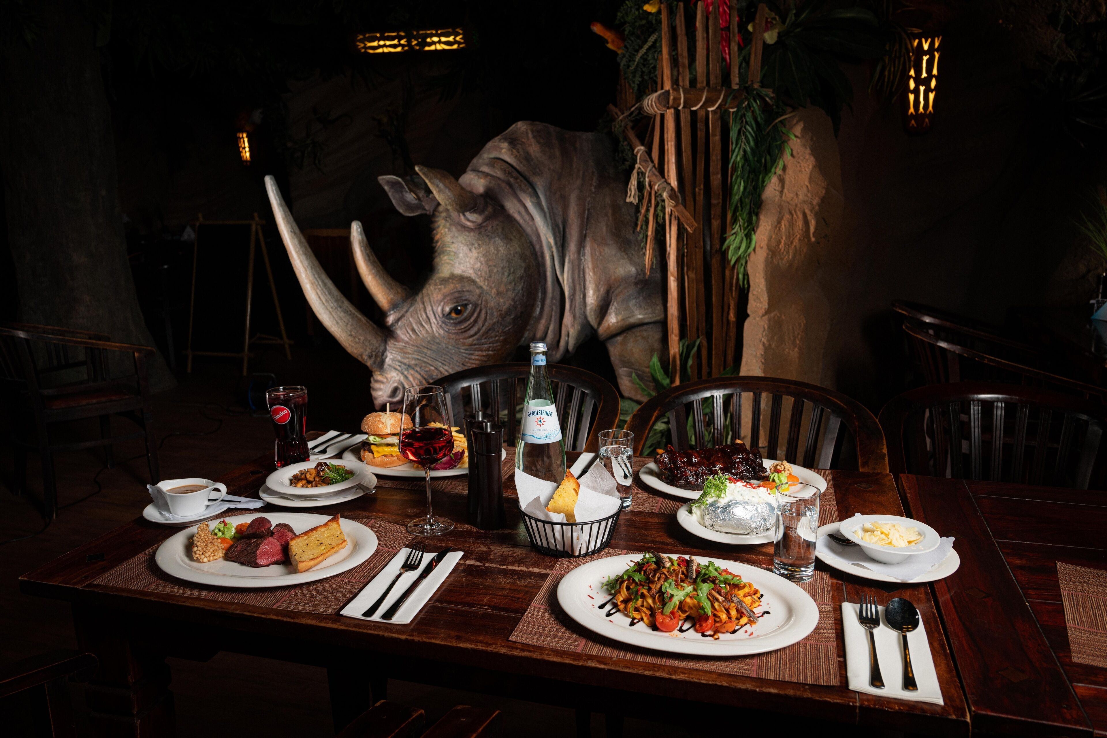 A dining table set with various dishes, a bottle of water, and a decorative animal head.