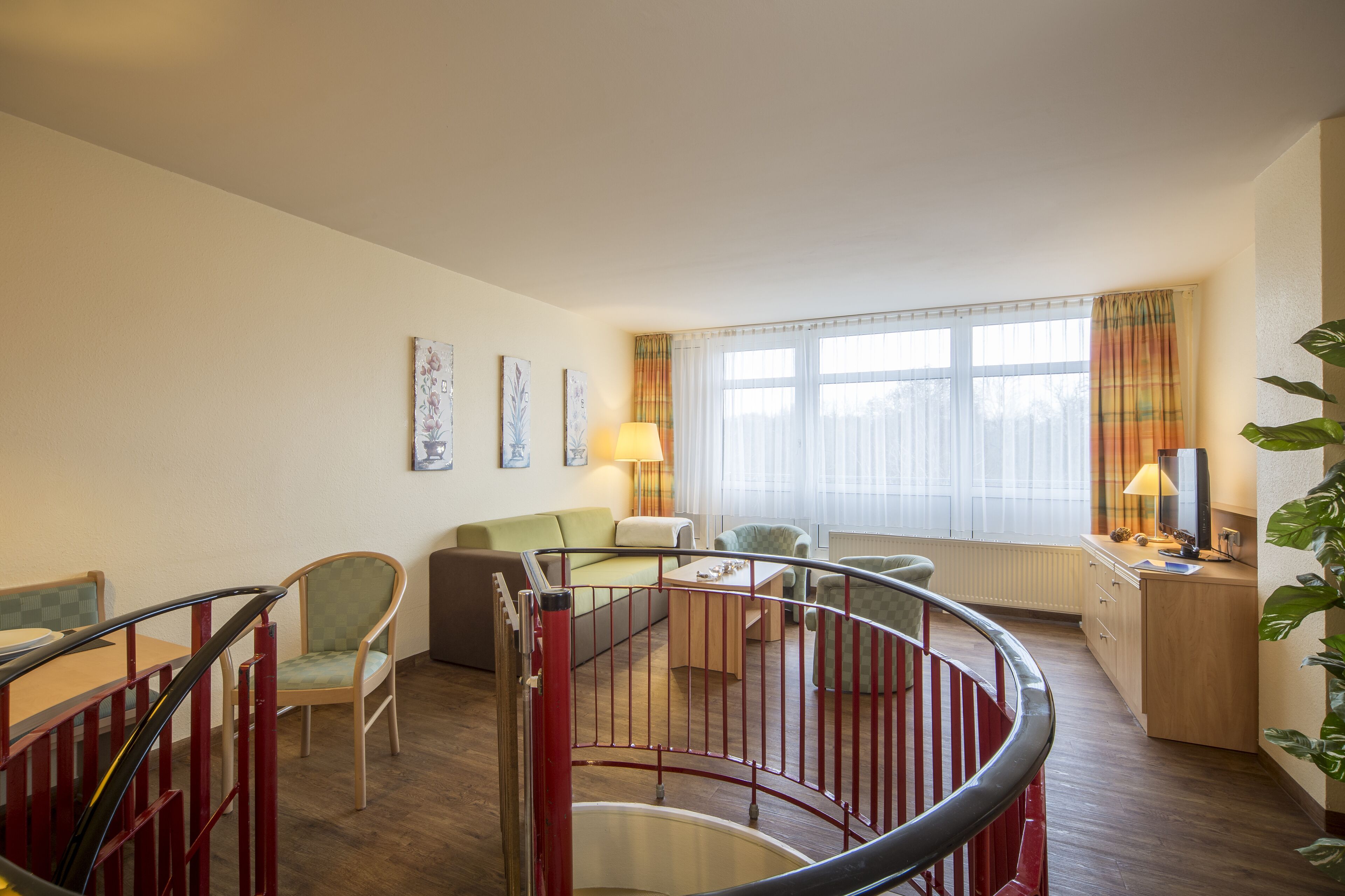 Un salón amplio con escalera, un sofá, una mesa de centro y un televisor sobre un mueble de madera.