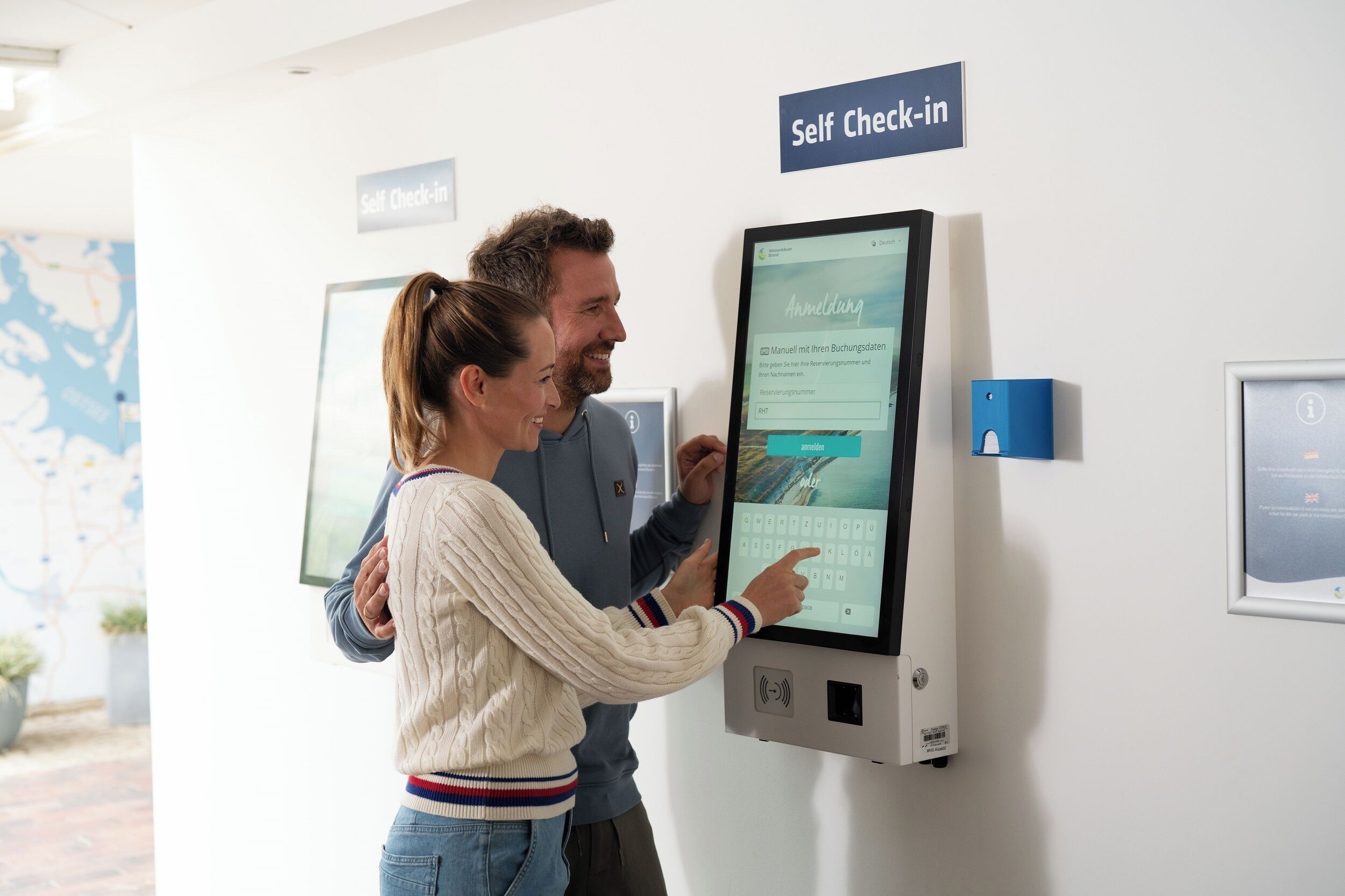 A digital kiosk with a screen displaying a form titled "Anmeldung" for registration or check-in.