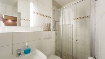 A bathroom with a shower, toilet, sink, and a mirror.
