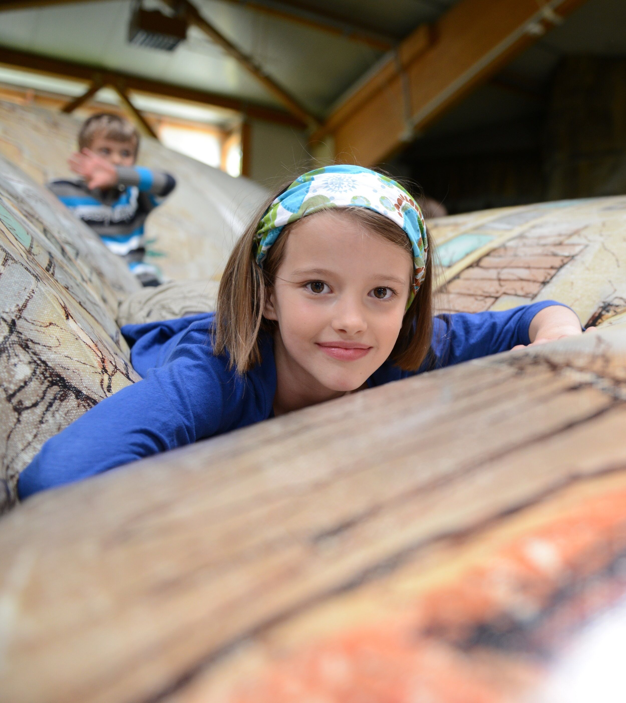 A child lying on a patterned couch in a room with wooden beams on the ceiling.