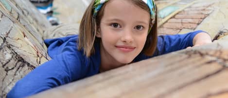 A child lying on a patterned couch in a room with wooden beams on the ceiling.