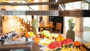 Un bufé de desayuno con diversas frutas, pasteles y quesos.