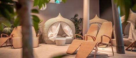 A spa area with wicker lounge chairs, a canopy bed, and a plant.