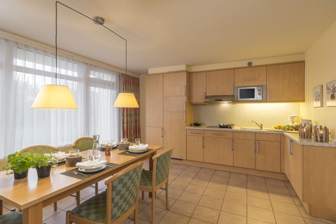 A modern kitchen with wooden cabinets, a microwave, and a dining area with a table and chairs.