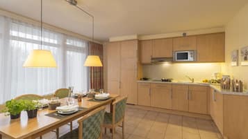 Una cocina moderna con armarios de madera, un microondas y una zona de comedor con mesa y sillas.
