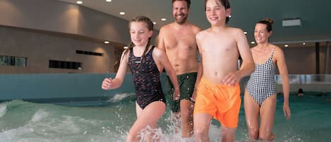 Una familia de cuatro personas en un área de piscina con un diseño interior moderno, que incluye un techo alto e iluminación empotrada.