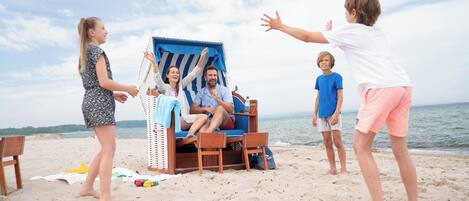 Escena de playa con una silla y una mesa, una botella y una bolsa.