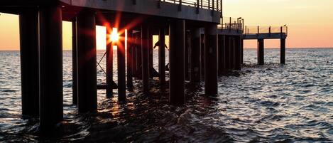 A pier extending into the water with a sunset in the background.