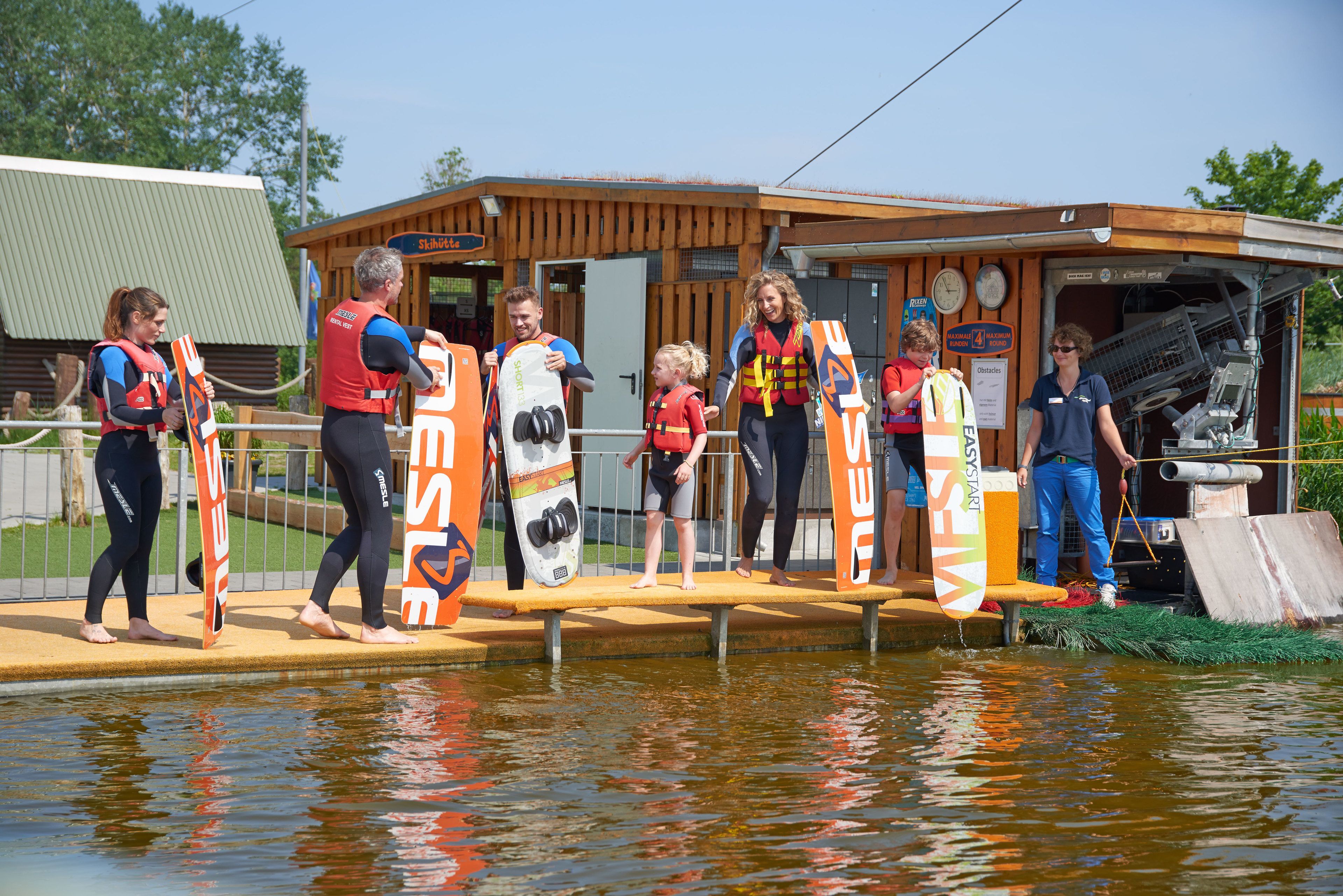 A wooden building with a sign that reads "Skiklubbe" and a pool with people standing on a platform.