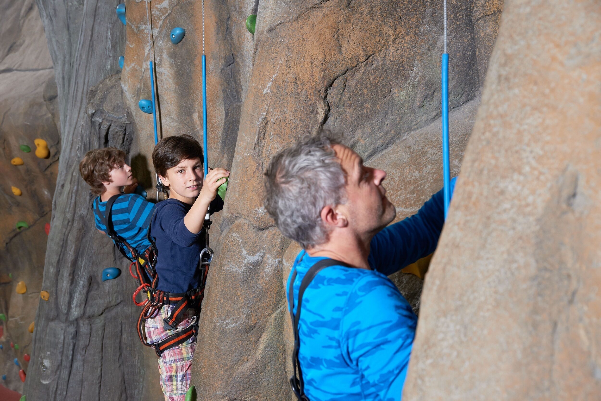 Una parete di arrampicata con appoggi di diversi colori e una persona che scala.