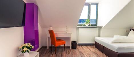 Una habitación moderna con techo inclinado, un escritorio, una silla, una cama y una ventana con vistas.