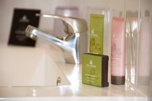 Un lavabo de baño con un grifo moderno, una caja verde etiquetada 'ALGOTHERM' y dos tubos de crema rosa.